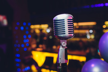Retro microphone against blur colorful light restaurant background.