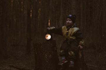 Fototapeta premium little baby alone in the dark forest with a flashlight