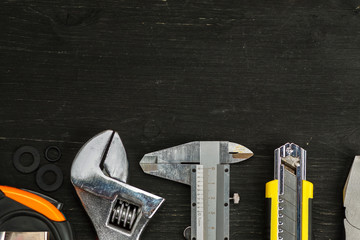 Different tools on a black wooden background, top view, space for text