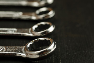 Set of different wrenches on a black wooden background, text space