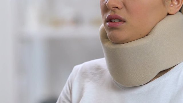 Upset woman in foam cervical collar talking phone, feeling neck pain, trauma