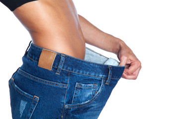 young woman in blue jeans showing her belly. Weight loss concept