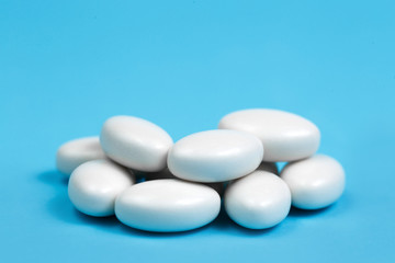 Heap of white pills on blue background. Medical, pharmacy and healthcare concept.