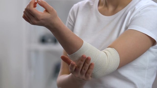 Woman wearing elastic wrap on painful elbow, arthritis problems, sickness