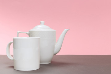 vintage white porcelain teapot and cup on a gray board and pink background