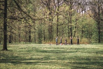 Group of people doing exercises in city park. Sunny day.