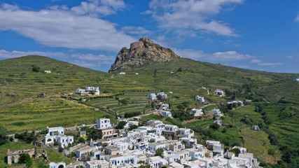 Fototapeta na wymiar Aerial drone photo of picturesque village of Tripotamos in the slopes of mountain and of Exomvourgo or Exombourgo with beautiful deep blue sky, Tinos island, Cyclades, Greece