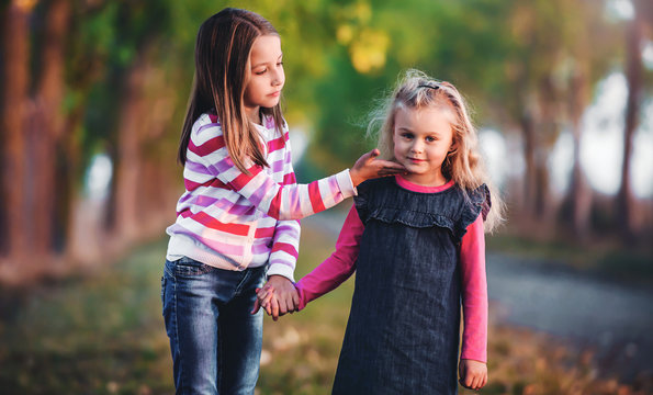 Two little girls walks together in the park. Childhood, nature, lifestyle