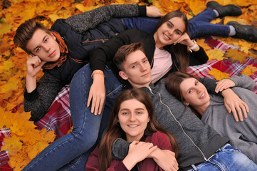 Girls and boys lie in the autumn leaves