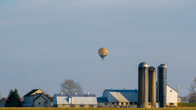Hot air balloon floating above an Amish farm house, Lancaster County, PA