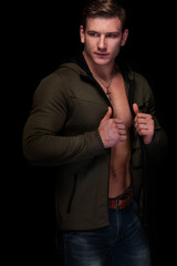 Handsome fit man posing wearing in jeans with tattoo. Sport and fashion concept isolated on black background.