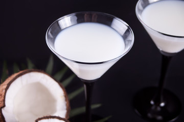Pina Colada cocktail on the black table with palm leaf and coconut on the background