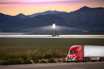 An eighteen wheeler with the future of renewable clean steam and solar energy in background 