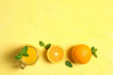 Flat lay composition with orange, mint and glass jar with fresh orange juice on color background, space for text. Fresh natural drinks