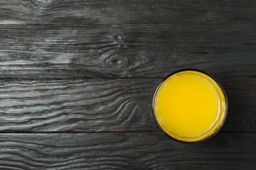 Glass of fresh orange juice on wooden background, space for text and top view. Fresh natural drink
