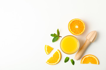 Flat lay composition with orange juice, orange pieces, mint and wooden juicer on white background, space for text. Natural drinks and fruits