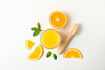 Obraz na płótnie Canvas Flat lay composition with orange juice, orange pieces, mint and wooden juicer on white background, space for text. Natural drinks and fruits