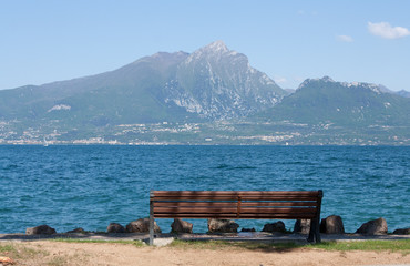Naklejka na ściany i meble Wooden bench on a lake. Garda lake, Italy.