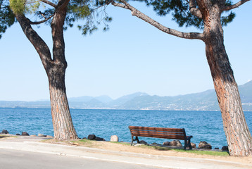 Fototapeta na wymiar Trees, bench and Garda lake at the backround. Italy.