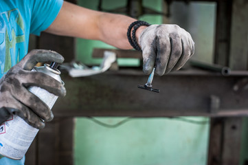 Worker with protective gloves painting the metal part