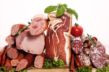 cold meat assortment with delicious salami and  fresh herbs . Variety of meat products including proscuitto, jamon  and sausages