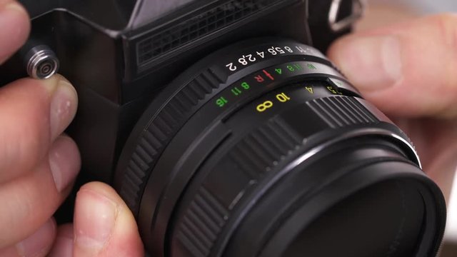 Hands of photographer uses a vintage USSR film camera, focuses and takes a picture. Close-up shot.
