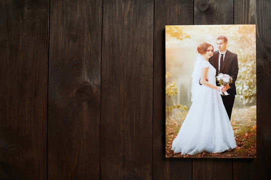 Photo canvas print. Wall decor. Sample of stretched wedding photography with gallery wrap. Bridal portrait hanging on brown wooden background. Front view with copy space