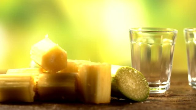 Brazilian gold cachaca pouring in glass cup. Sugar Cane Derivatives. Sugar and sugarcane on old wood background.
