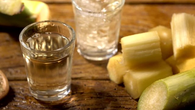 Brazilian gold cachaca pouring in glass cup. Sugar Cane Derivatives. Sugar and sugarcane on old wood background.