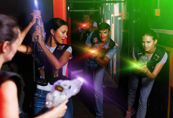 friends standing with laser guns during laser tag game - obrazy, fototapety, plakaty