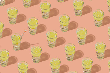 Glasses of cold water with ice and lemon. Repeating pattern on a pink background.