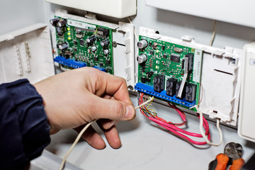 A hand connects the wire to the chip board. Repair, maintenance and adjustment of equipment by a...