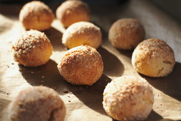 Round cottage cheese buns homemade lay on parchment paper in natural sunlight. Fresh pastries for healthy eating sprinkled with coconut crumb