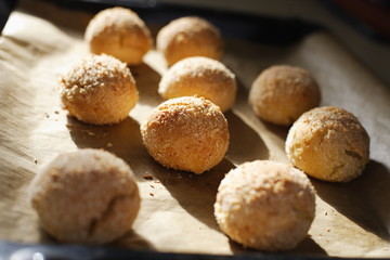 Round cottage cheese buns homemade lay on parchment paper in natural sunlight. Fresh pastries for healthy eating sprinkled with coconut crumb