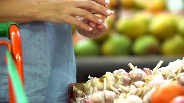 Woman's hand choosing Garlic in supermarket 