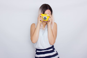 Blonde woman holding yellow retro camera