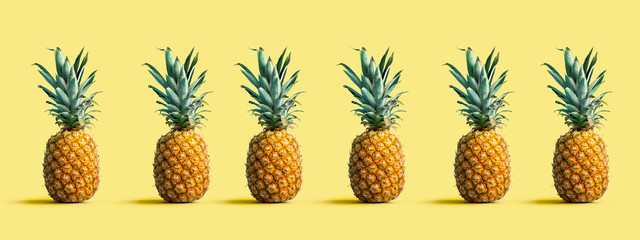 Many pineapples on a solid color background