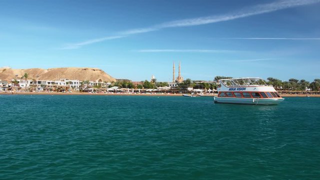 SHARM EL SHEIKH, EGYPT- DECEMBER, 2018: Retro yacht for rest. Against the backdrop of palm trees and hotels. A minaret and a mosque can be seen in the distance. Slow Motion.