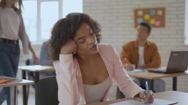 emaciated simple woman sleeps in a lecture. black girl wakes up with a sudden jolt. Group of students in the background 4K