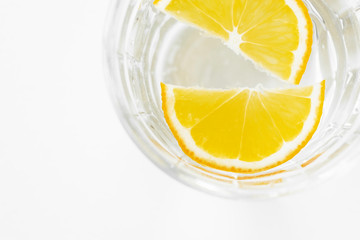 slices of lemon in a glass of water, close-up. sliced lemon in faceted glass with water on white background