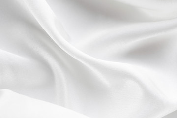 white silk texture. background of white fabric lying folds on the table