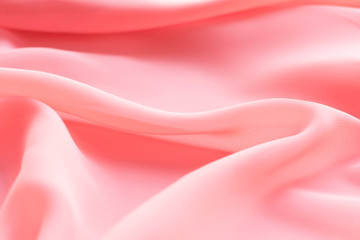 pink silk texture. background of coral fabric lying folds on the table