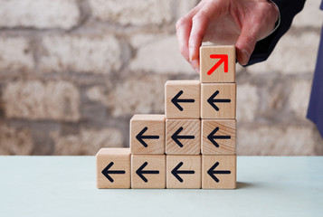 Businessman hand picked wooden block with red arrow facing the opposite direction black arrows,...