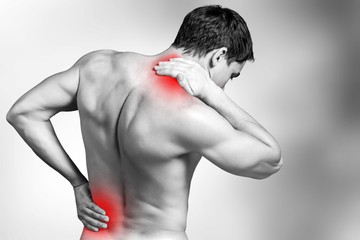 Back view of shirtless man touching his aching back and neck