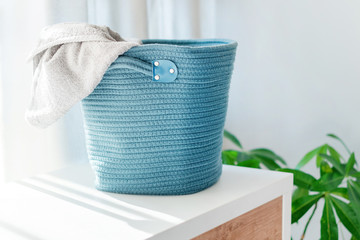 Laundry basket with gray towel. Interior of white stylish room with laundry basket