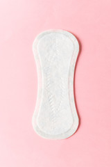 Feminine hygiene pad on a pink background. Concept of feminine hygiene during menstruation. top view.