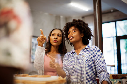 Female friends discussing while standing in cafe