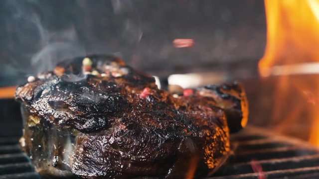 Large grains of pepper fall on juicy grilled filet mignon. Hot juicy oil steak cooking. Caucasian kitchen tasty beefsteak, delicious juicy meat. Street food cooked on hot plate. close up slow motion