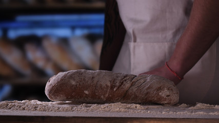 In the bakery, the hands of the baker are seen very closely as he prepares various flour products in an apron, after which he lays on the shelf. Concept of: Fresh Bread, Pizza, Bakery, Slow Motion.