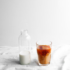 Bottle with milk and glass cup with coffee on the table. cold brew iced coffee